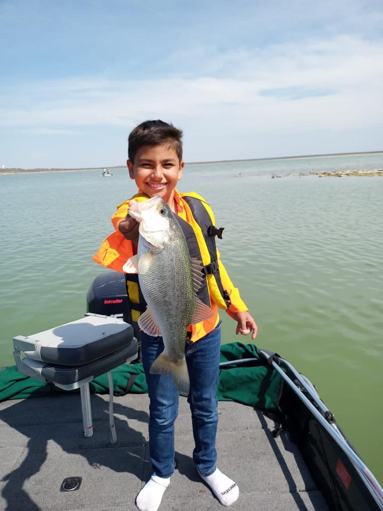 boy shows his trophy of largemouth bass caught at El Cuchillo Lake, La China, Nuevo Leon