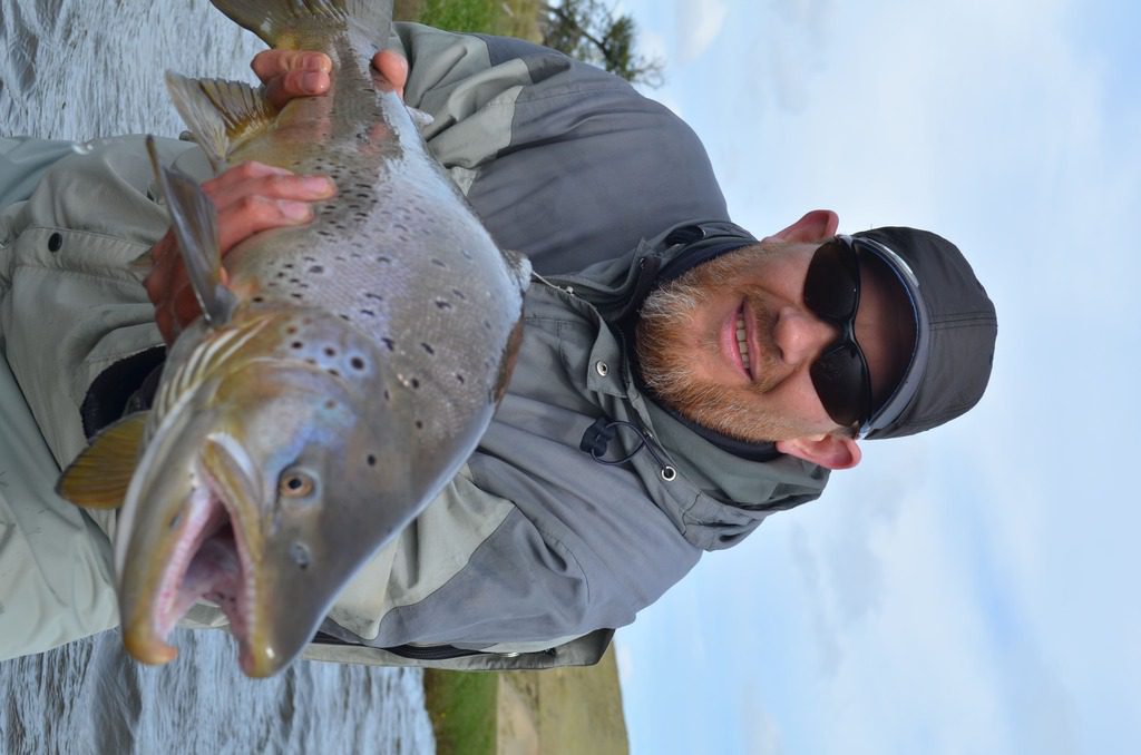 Angler proud of his catch of rainbow trout at Chepelmut Creek, Tierra del Fuego, Argentina